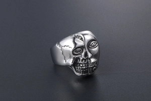 Vue détaillée d'une bague en acier avec relief 3D de crâne et visage humain sculpté