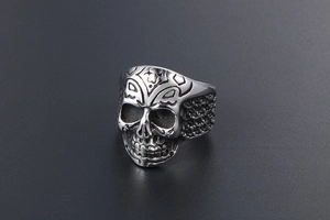 Macro detail of gothic skull ring featuring geometric engraving and woven texture band