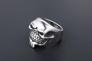Detailed close-up of a bearded skull ring in polished silver steel with gothic details