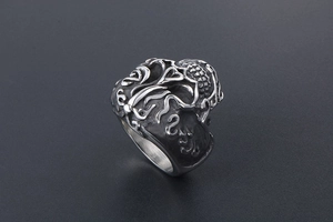 Macro view of gothic skull ring showing detailed floral relief and vintage steel texture