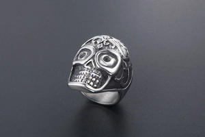 Detailed view of vintage skull ring with intricate floral carvings and punk aesthetic