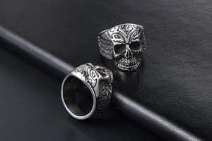 Detailed macro shot of vintage skull ring with tribal patterns on black leather texture