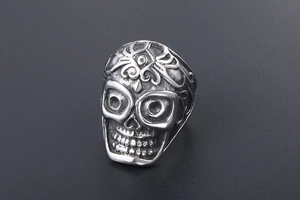 Macro detail of gothic skull ring featuring vintage vine patterns and aged steel texture