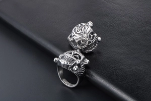 Close-up of vintage lion and skull rings with textured metal on black leather background
