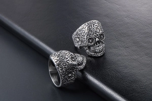Macro detail of vintage sugar skull rings with intricate floral engraving on steel