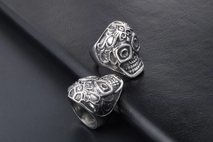 Macro close-up of vintage silver skull ring with gothic patterns on black leather background