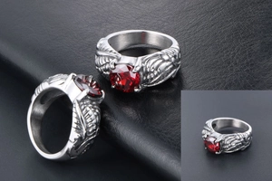 Detail of vintage wing ring with red gemstone and silver engraved texture on black leather