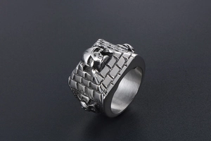 Macro shot of retro skull climbing a brick wall relief on stainless steel punk ring
