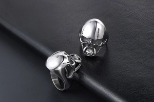 Detailed view of skull rings with vintage finish on textured black leather surface
