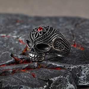 Gothic skull ring for men in vintage steel with a ruby red gemstone and lava background