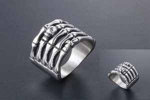 Macro shot of silver punk ring featuring detailed skeleton hand and skull bone design