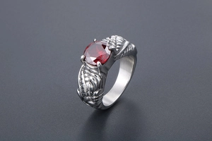 Macro detail of vintage silver dragon claw ring featuring a large faceted red gemstone
