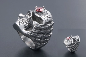 Detailed view of punk gothic steel skull ring with large red gemstone and carved scales