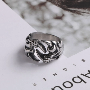 Detail of vintage dragon claw titanium steel ring showing intricate scale textures on a page