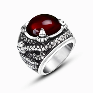 Macro detail of gothic dragon claw ring featuring a large round red gemstone and scales