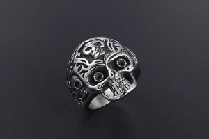 Makroaufnahme des Vintage-Totenkopfrings mit Reliefdetails und dunklen Ranken