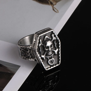 Close-up of vintage silver skull ring with coffin-shaped top and gothic biker textures