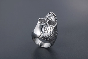 Macro shot of punk style steel skull ring featuring textured scales and polished finish