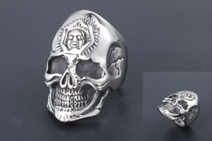 Close-up of vintage punk skull ring with intricate sun pattern and face relief engraving