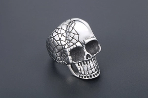Macro detail of men's skull ring showing split textures of scales and polished finish