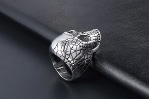Close-up of gothic silver skull ring featuring cracked texture and heavy metal band