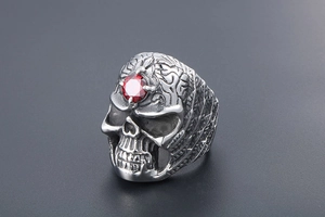 Detailed view of gothic skull ring featuring a red gemstone inlay and silver textured scales