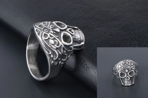 Close-up of vintage punk skull ring with detailed vine engravings on silver steel surface