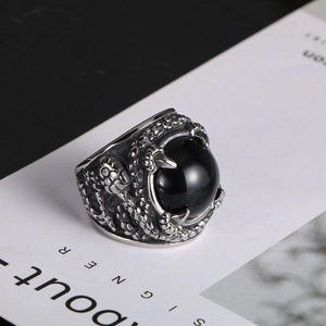 Macro detail of gothic dragon claw ring holding a polished black stone sphere