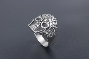 Detailed close-up of punk skull ring with ornate floral engravings in retro steel