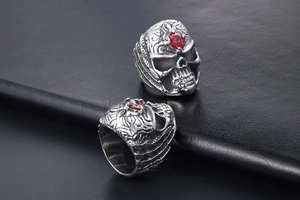 Macro detail of gothic skull ring with red gemstone inlay on black leather background