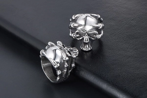 Detailed view of punk skull rings in polished stainless steel on black leather texture