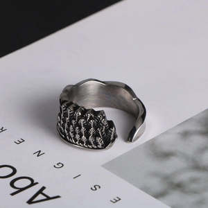 Macro shot of silver adjustable wing ring with embossed textures on a magazine background