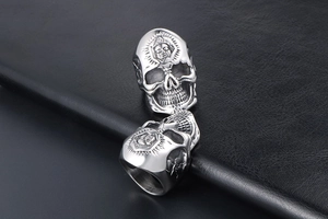 Macro detail of gothic skull rings with face relief on black leather background