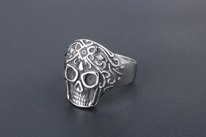 Macro detail of vintage punk skull ring with intricate floral carvings on matte steel