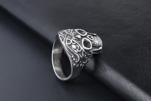 Detailed side view of a vintage silver skull ring with gothic patterns on black leather