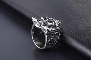 Detailed close-up of a silver skull and crossbones ring on a black leather background