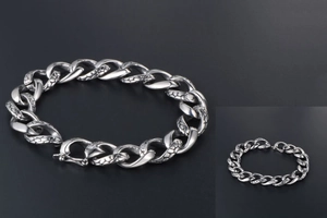 Macro detail of silver gothic cuban chain bracelet with snake skin texture and square clasp