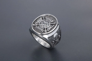 Close-up of punk style stainless steel ring featuring skull relief and heraldic emblem