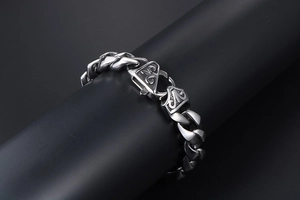 Détail du bracelet gourmette en acier avec fleur de lys gothique gravée sur le fermoir