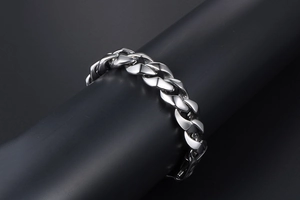 Détail macro du bracelet gourmette en acier poli argenté sur support d'affichage