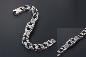 Macro view of silver punk chain bracelet showing Buddhist symbols and spring clasp