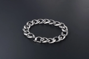 Detail of gothic silver steel cuban link bracelet with snake scale engraved texture