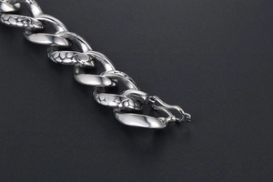 Macro view of vintage silver snake pattern texture on a flat Cuban link chain bracelet