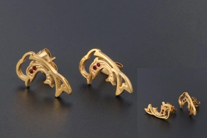 Detailed view of 18K gold plated dolphin stud earrings with red crystal eyes