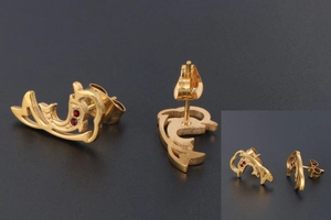 Close-up of 18K gold dolphin earrings featuring sparkling red crystals and butterfly backs