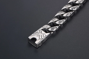 Macro detail of Buddhist mantra engraving on punk vintage stainless steel chain bracelet