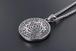 Dettaglio del ciondolo stella vintage con segni zodiacali incisi su catena d'acciaio