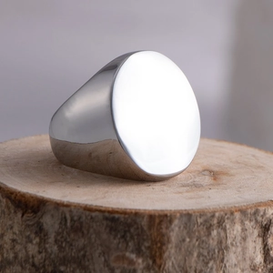 Minimalist silver polished stainless steel signet ring for men on a natural wood base