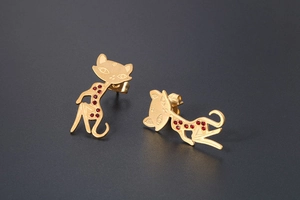 Detailed close-up of golden cat stud earrings with red gemstones and matte finish