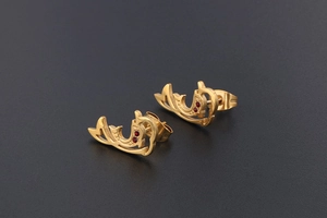 Macro detail of 18K gold dolphin earrings with sparkling red zircon gemstones